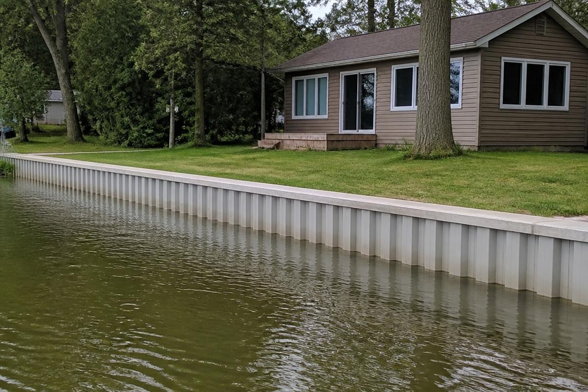 Vinyl sheet-pile seawall with a concrete cap along the shoreline of a modest lake cottage